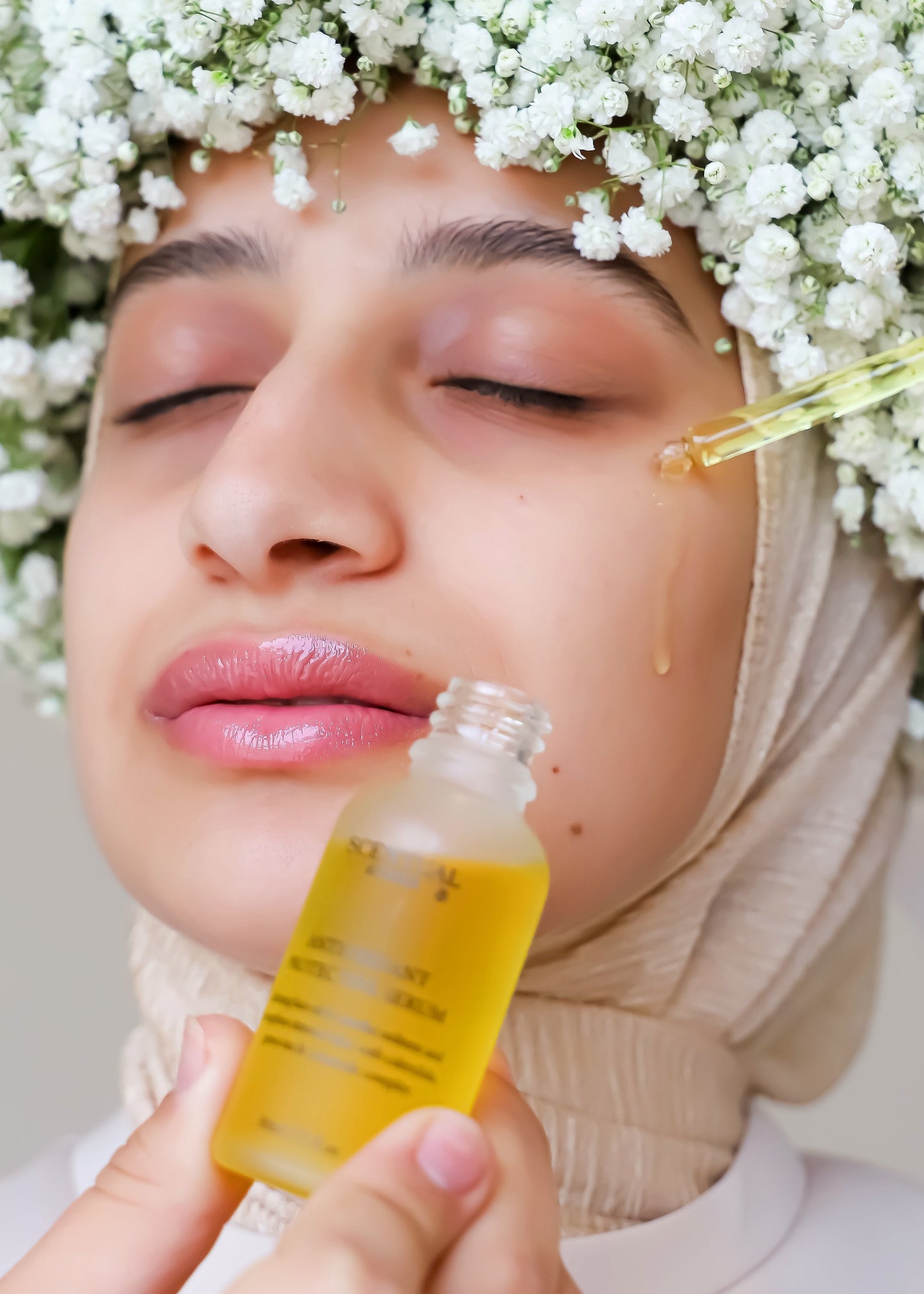 Woman applying a skincare serum with flowers around her head